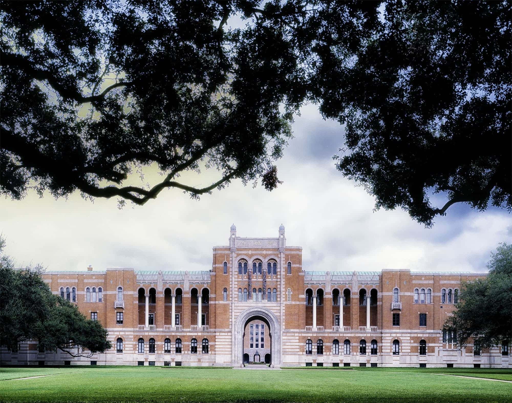 A grand historical architecture in a middle of field with framing trees.